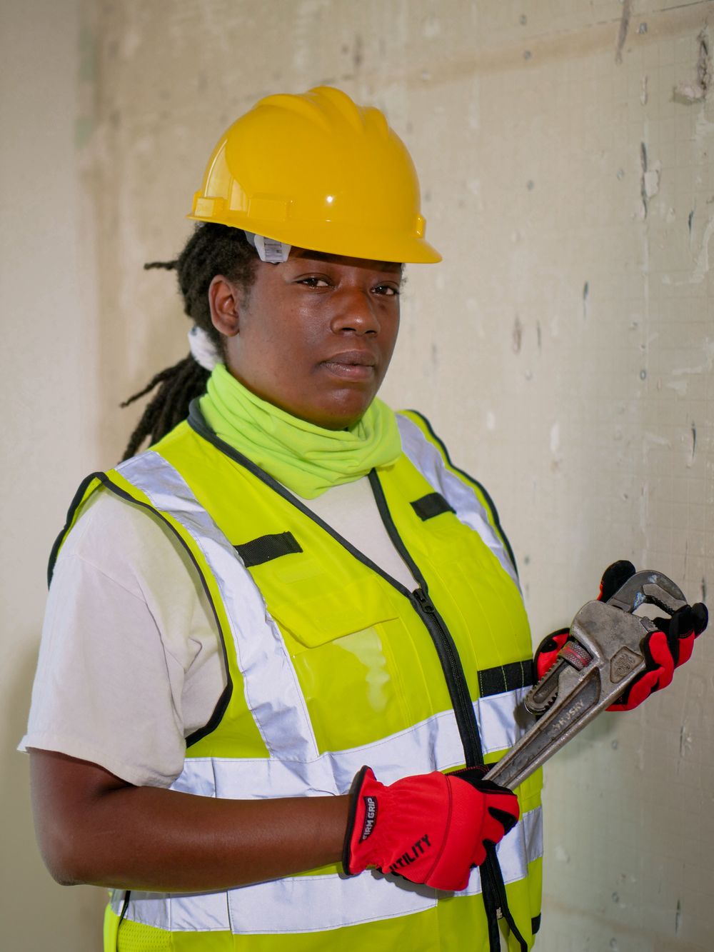 Plumber in a high-visibility vest holding a pipe wrench