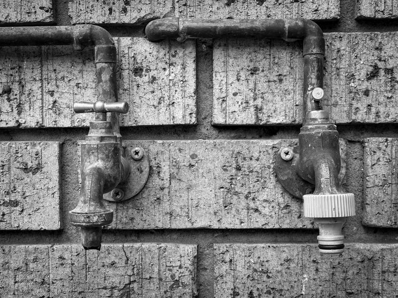 Two isolation valves and pipework mounted on a brick wall